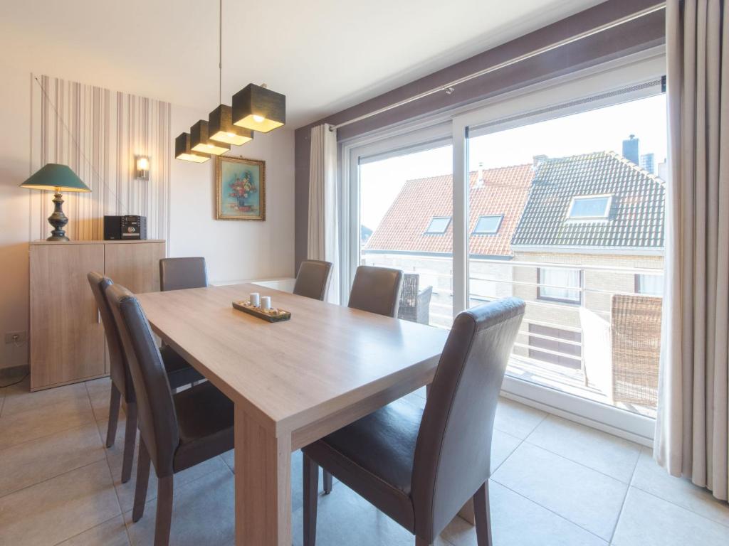 a dining room table with chairs and a large window at Apartment Zeebries by Interhome in Bredene