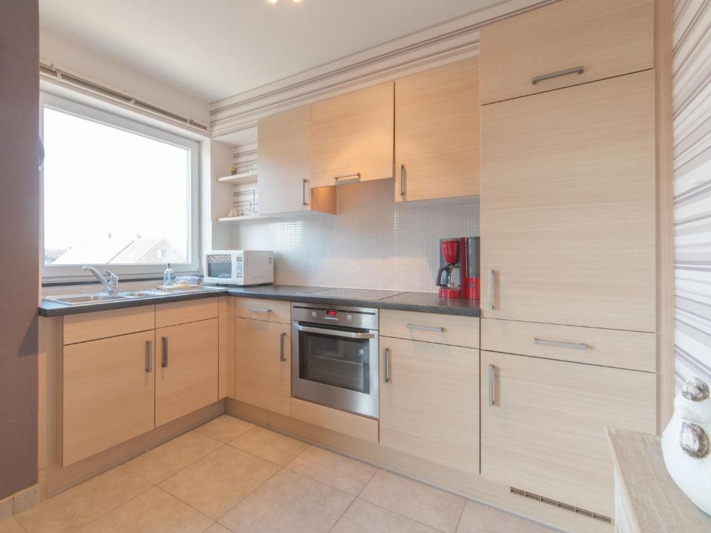 a kitchen with wooden cabinets and a window at Apartment Zeebries by Interhome in Bredene
