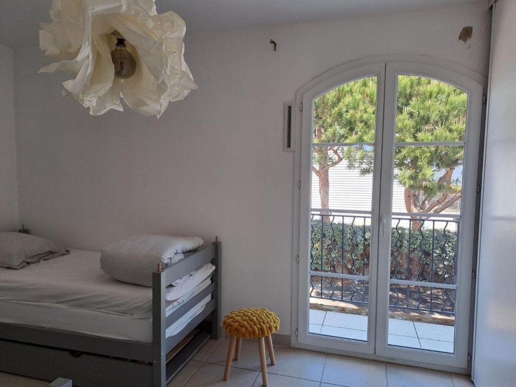 a bedroom with a bed and a sliding glass door at Belle marina avec ponton et piscine collective in Aigues-Mortes