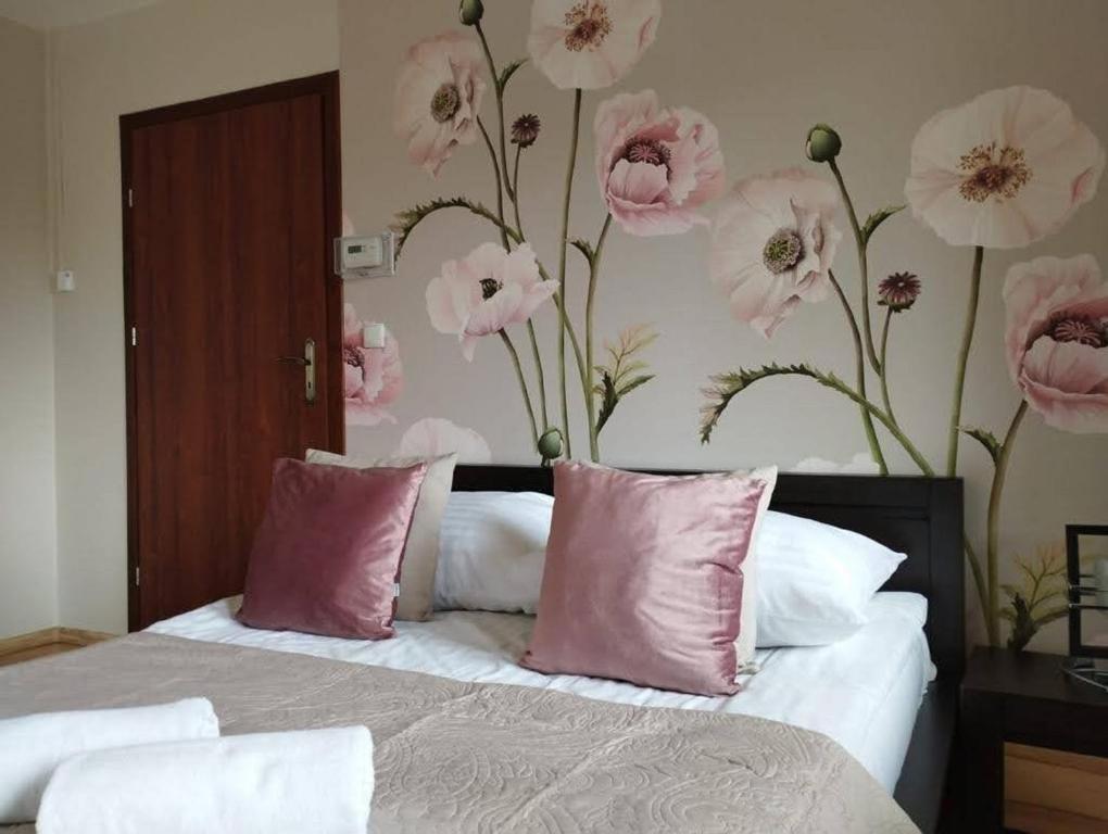ザコパネにあるApartament na Antałówceのベッドルーム1室(ピンクの枕と花の壁付)
