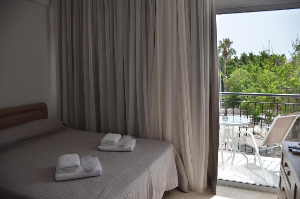 a bedroom with a bed and a balcony with a view at Almyria Apartments - By IMH Travel & Tours in Paphos