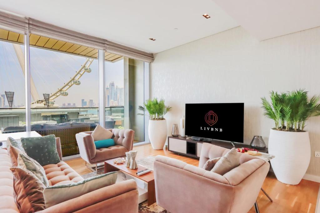 - un salon avec canapés, télévision et fenêtres dans l'établissement Bluewater Island - Bright 2 BR Suite with Dubai Eye View by Livbnb, à Dubaï