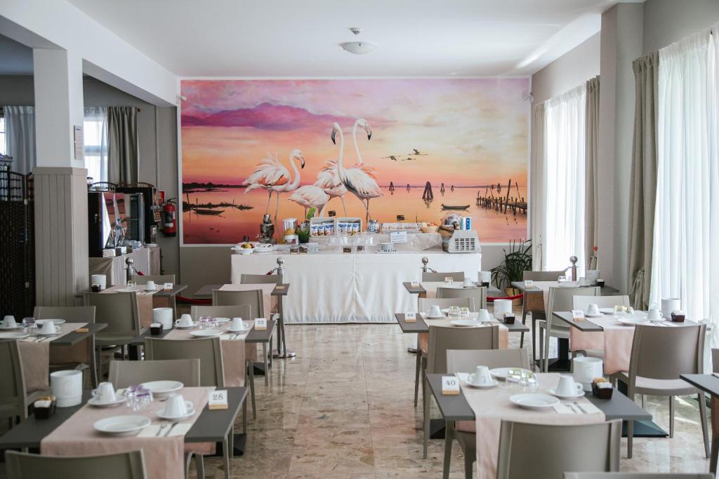 un restaurante con mesas y sillas y una pintura de flamencos en Hotel Laura, en Cavallino-Treporti