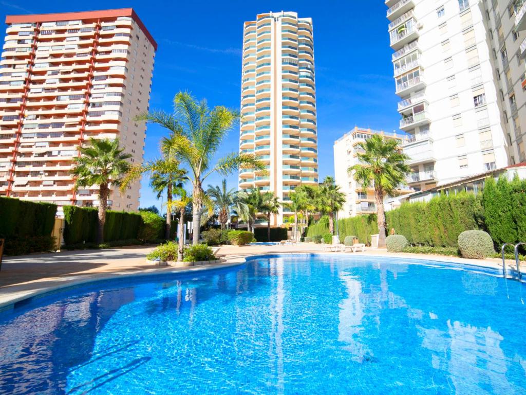 une grande piscine bordée de palmiers et de grands bâtiments dans l'établissement Apartment Esmeralda Suites-4 by Interhome, à Calp