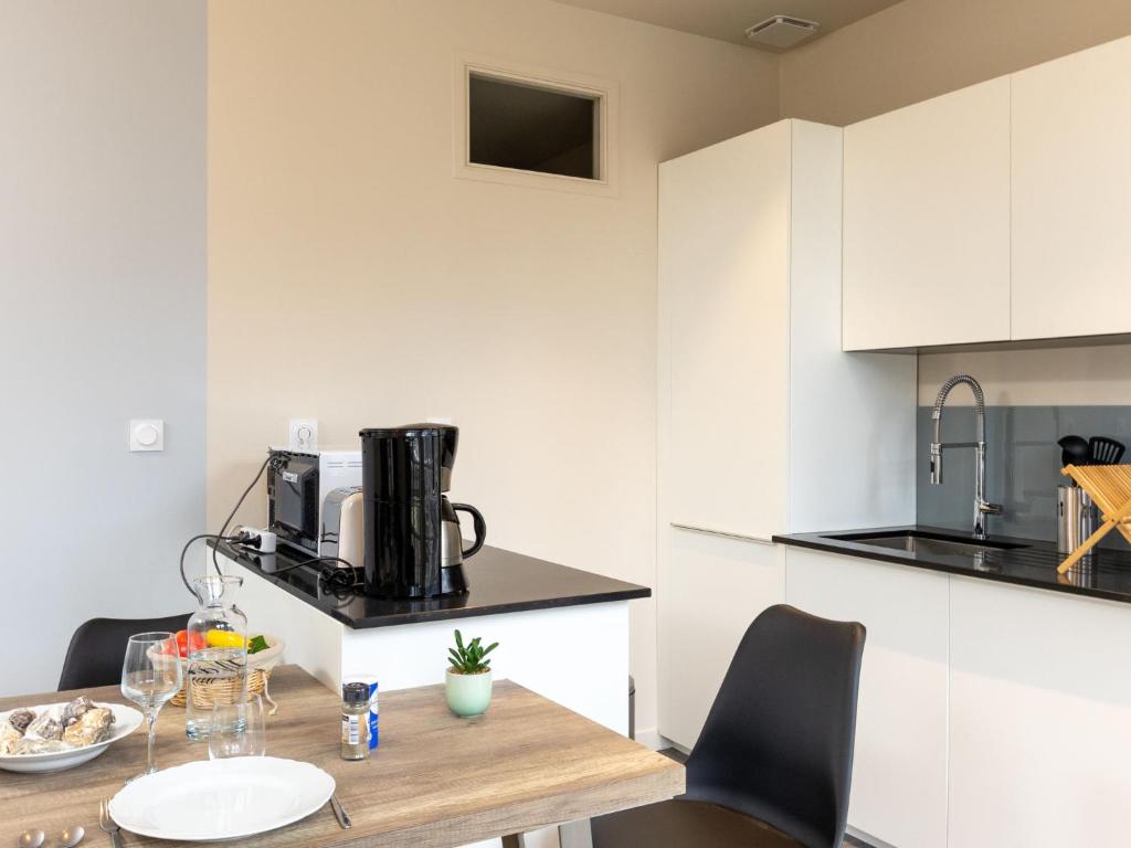 a kitchen with white cabinets and a wooden table and chairs at Apartment Plasenn by Interhome in Saint Malo