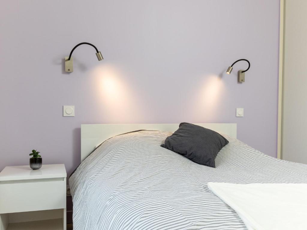 a white bedroom with a bed with a black pillow at Apartment Plasenn by Interhome in Saint Malo