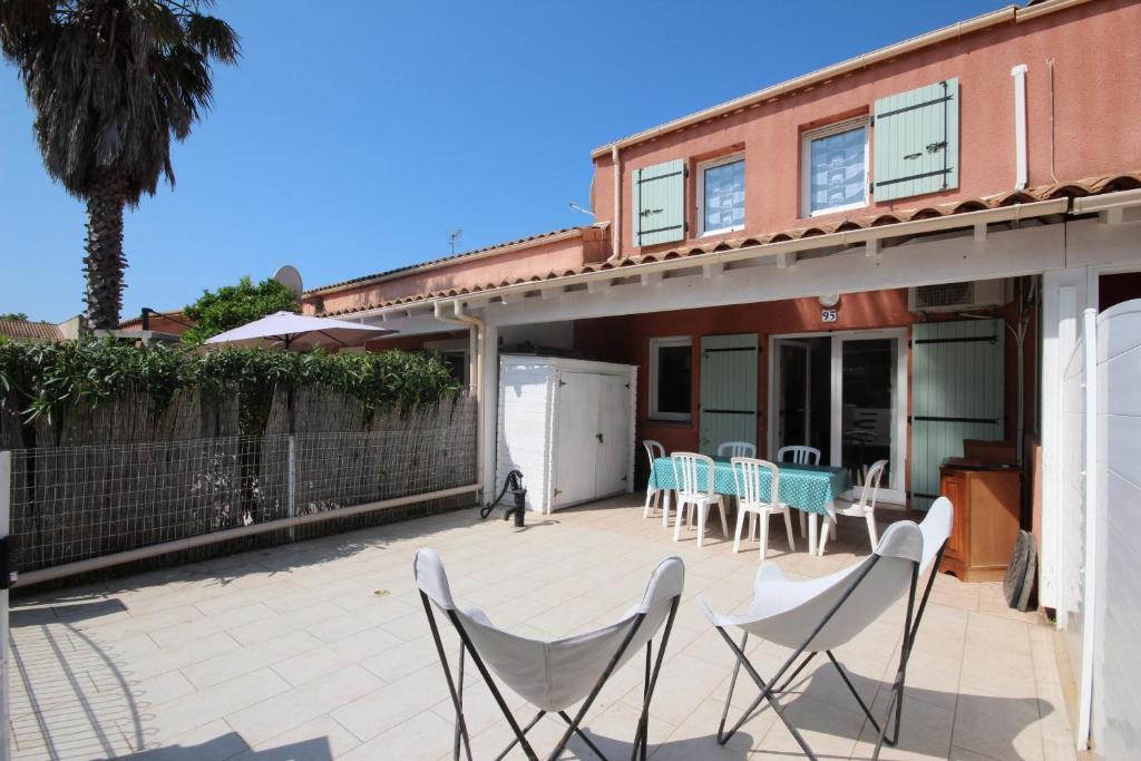 une terrasse avec des chaises et des tables dans une maison dans l'établissement Agréable Maison de vacances climatisee, 2 chambres pour 5 couchages, Résidence securisee avec piscine commune LE CLOS DE SOCORRO, 800m de la plage Portiragnes plage LRCS95, à Portiragnes