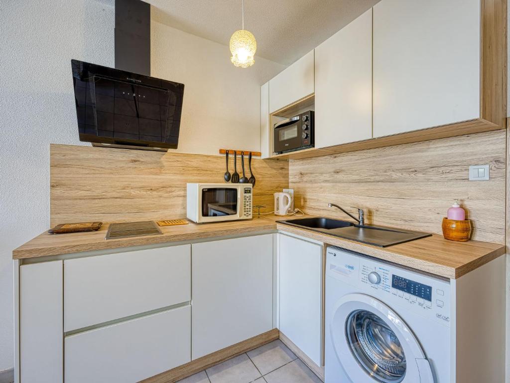 a kitchen with a washing machine and a microwave at Apartment Le Sunset-Cap Sud-23 by Interhome in Cap d&#39;Agde