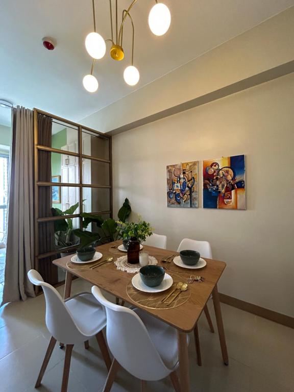 une salle à manger avec une table en bois et des chaises blanches dans l'établissement Jhezzstuffs staycation, à Iloilo