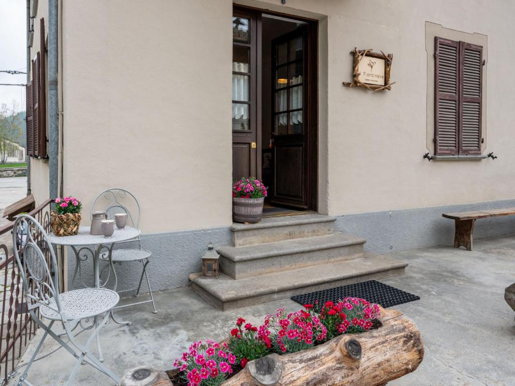 - une terrasse couverte avec une table, des chaises et des fleurs dans l'établissement Apartment Il Fior di Neve by Interhome, à Prali