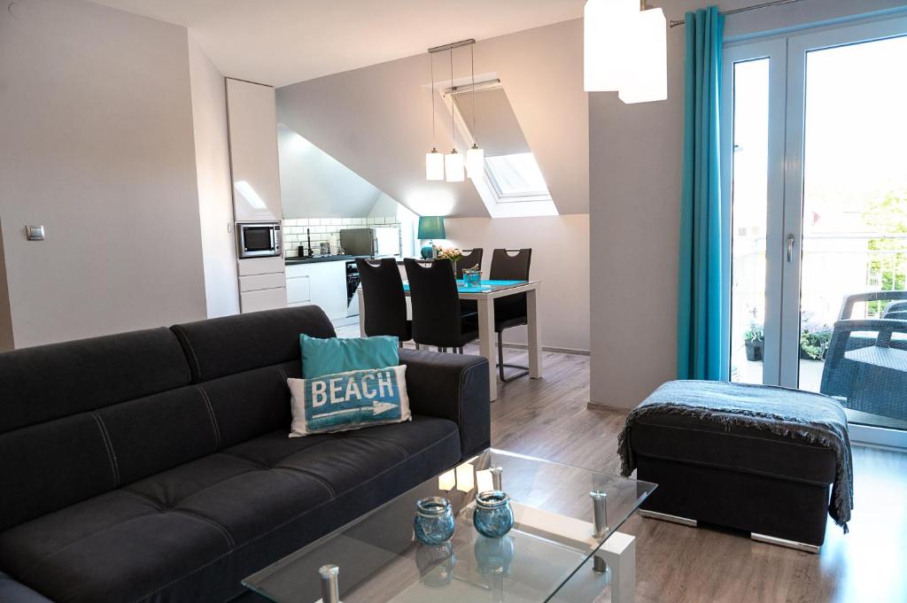 a living room with a black couch and a table at Turkus Holiday in Pobierowo
