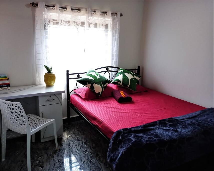 Schlafzimmer mit einem roten Bett, einem Schreibtisch und einem Fenster in der Unterkunft Tulsi Authentic Homestay - Beach Village Goa in Canacona