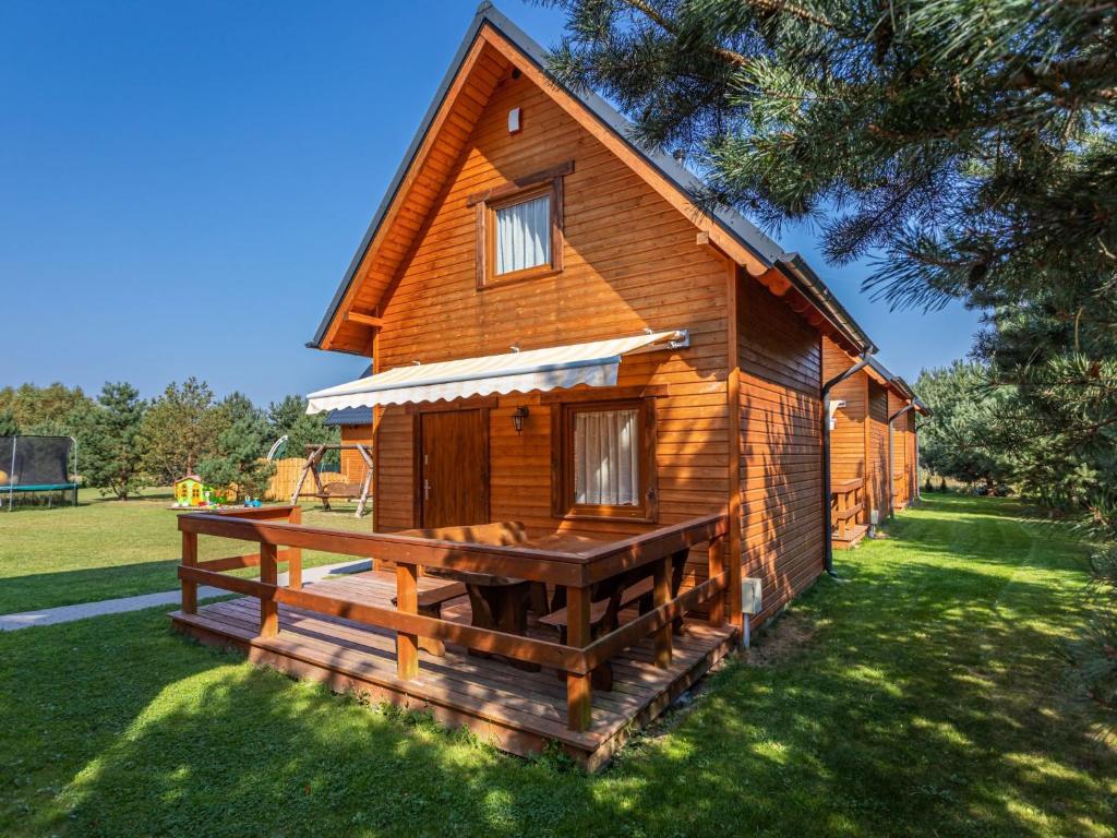 a wooden cabin with a large deck in the grass at Holiday Home Domki Miłe-1 by Interhome in Choczewo