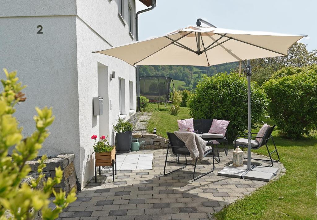 a patio with two chairs and an umbrella at Ferienwohnung Familie Strehl in Frickingen