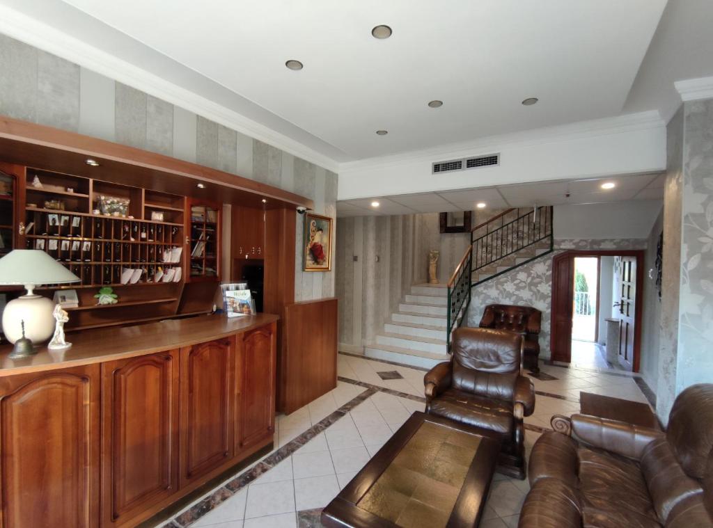 a living room with leather furniture and a staircase at Fortuna Hotel in Miskolctapolca