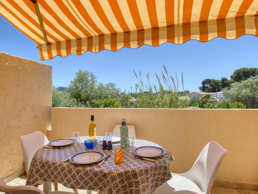 une table avec des chaises et un parasol sur une terrasse dans l'établissement Studio Les Lavandes-17 by Interhome, à Saint-Cyr-sur-Mer