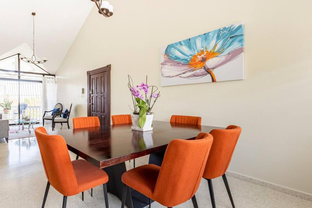 a dining room with a table and orange chairs at Paramount Views in San Felipe de Puerto Plata
