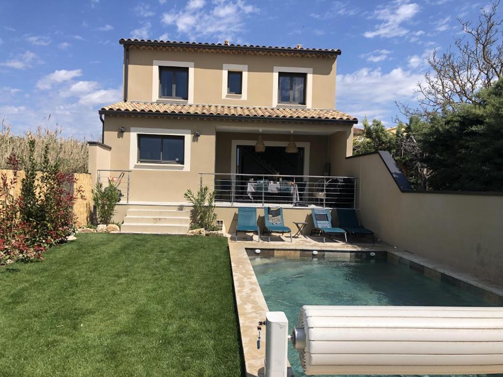 a house with a swimming pool in front of a yard at La maison Adriel - Villa récente avec jardin et piscine in Saumane-de-Vaucluse