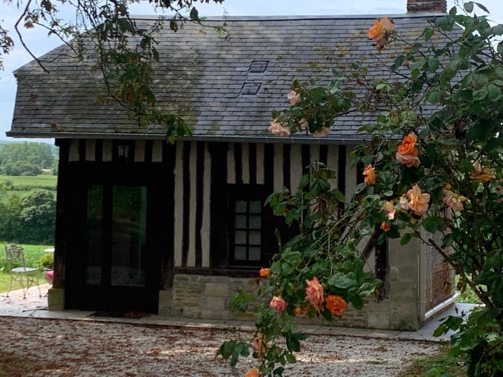 een zwart-wit gebouw met een raam en bloemen bij La Bouillerie du Manoir des Bréholles in Goustranville