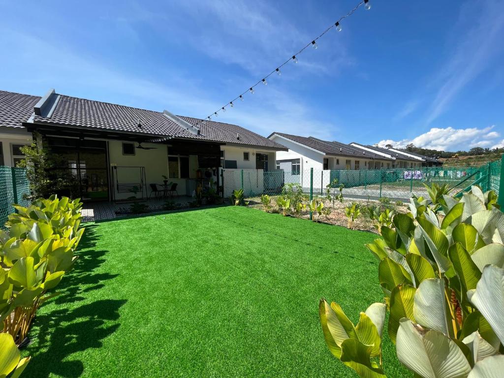 einen großen Hof mit grünem Gras und Häusern in der Unterkunft Tun Teja Homestay Jasin Melaka in Jasin