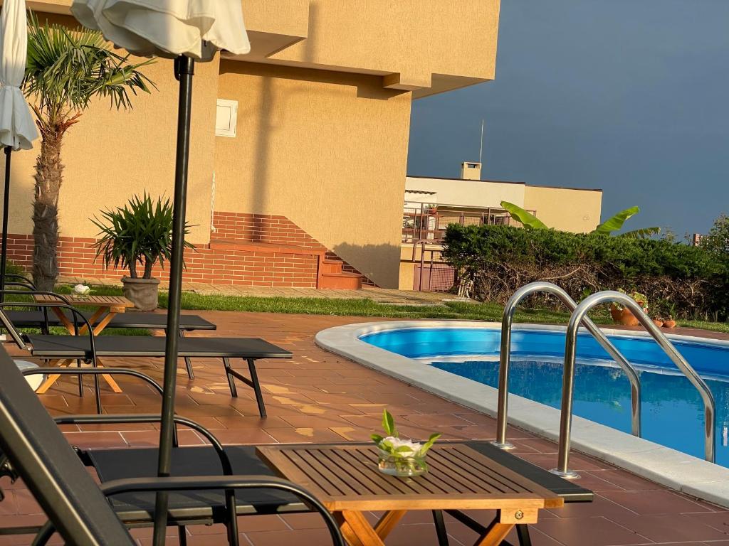 un patio con mesa y sillas junto a una piscina en Villa Omnia, en Varna
