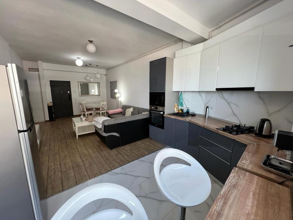 een keuken met witte kasten en een woonkamer bij Lavand Eighteen 3 in Mamaia Nord – Năvodari