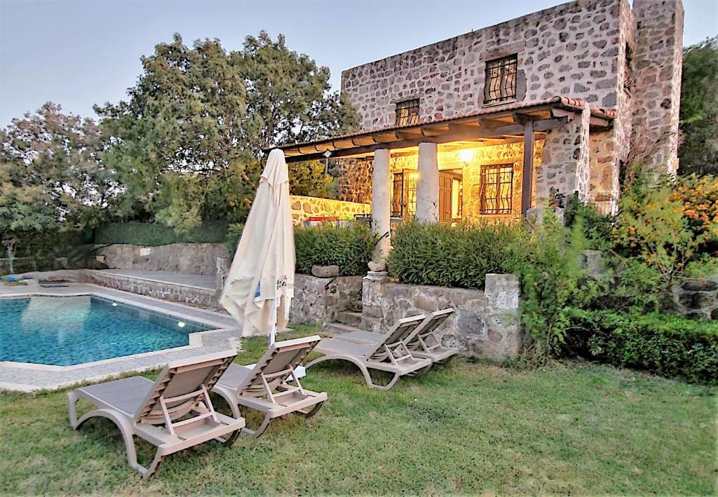 een huis met een zwembad en twee stoelen en een parasol bij Authentic Bodrum Villa with Special Private Pool in Ortakent