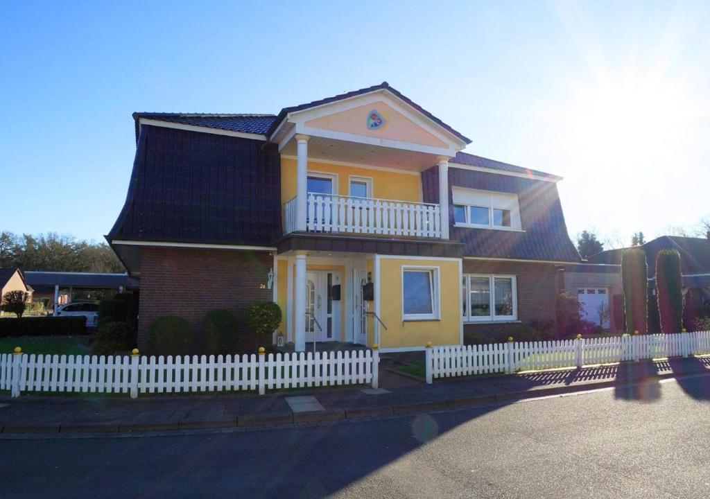 ein gelbes Haus mit einem weißen Zaun davor in der Unterkunft Alter Ziegelhof, Terrasse, WLAN, bis zu 9 Personen in Vechta