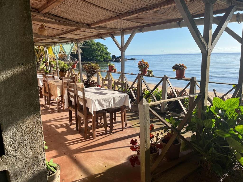 une terrasse avec des tables et des chaises et l'océan dans l'établissement Le Rocher, sur l'île Sainte-Marie