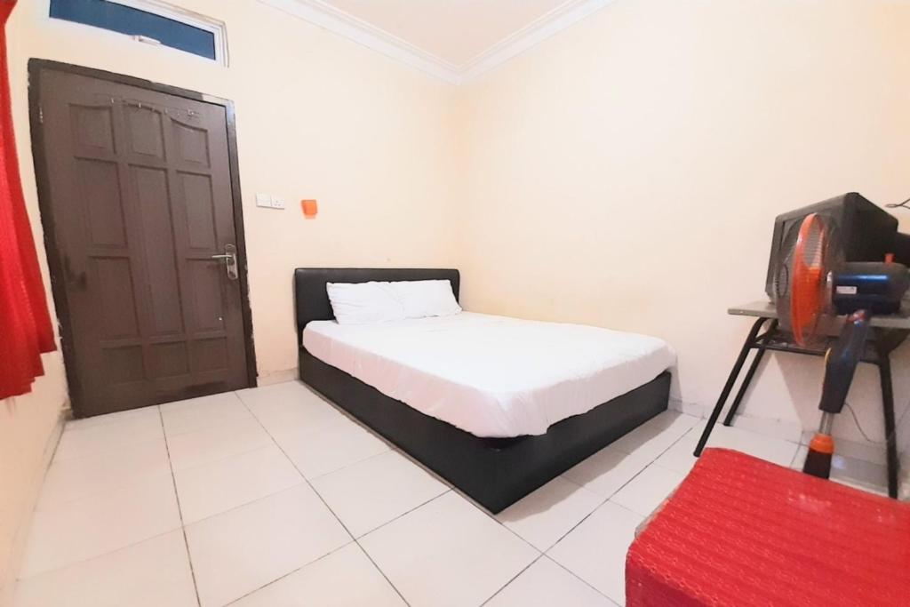 um quarto com uma cama e uma televisão em SPOT ON 92599 Pondok Anggrek Syariah em Pekanbaru