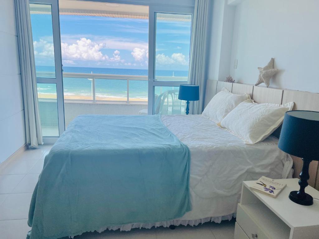 a bedroom with a bed with a view of the ocean at Brisa da praia ao lado Centro de Convenções in Salvador