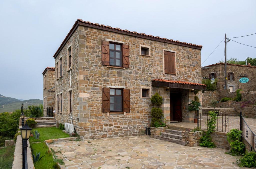 una antigua casa de piedra con un patio frente a ella en Salkım Otel Gökçeada en Gokceada Town