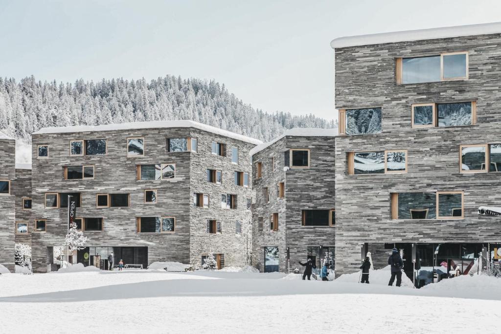 a group of people standing in the snow in front of buildings at rocksresort in Laax