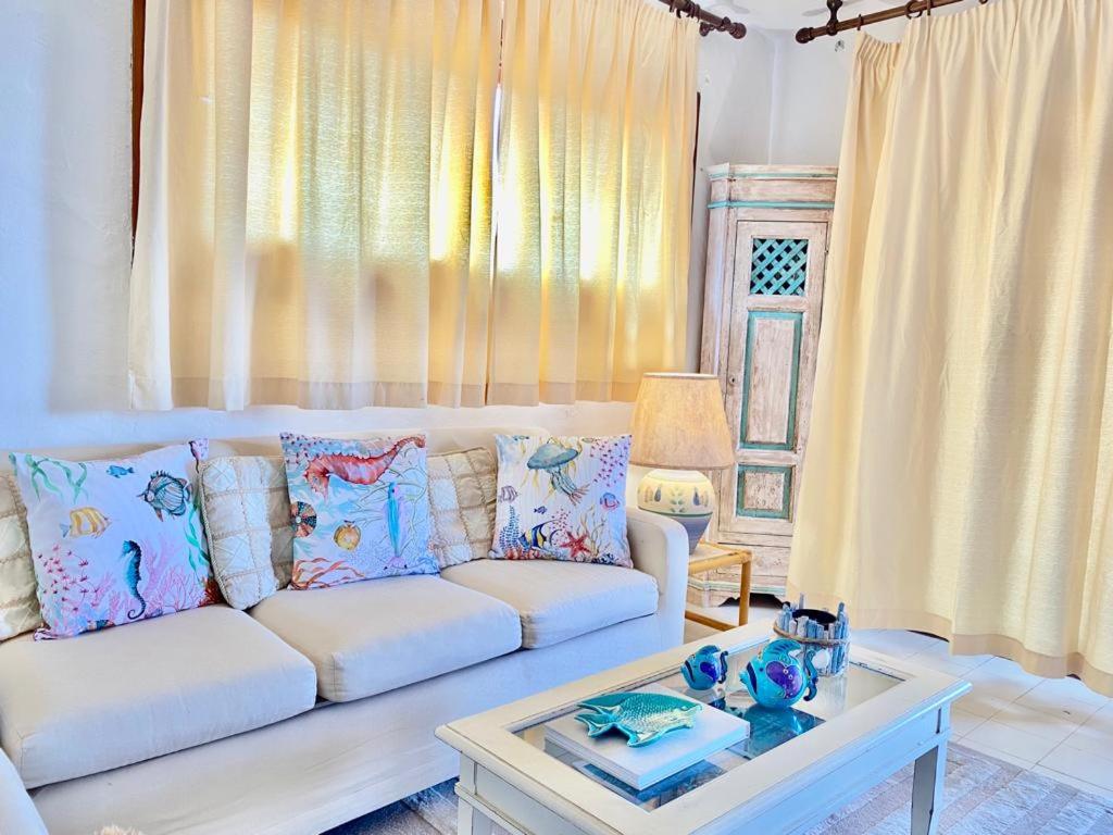 een woonkamer met een witte bank en een tafel bij Oasi Verde Acqua - Country Porto Rotondo in Porto Rotondo