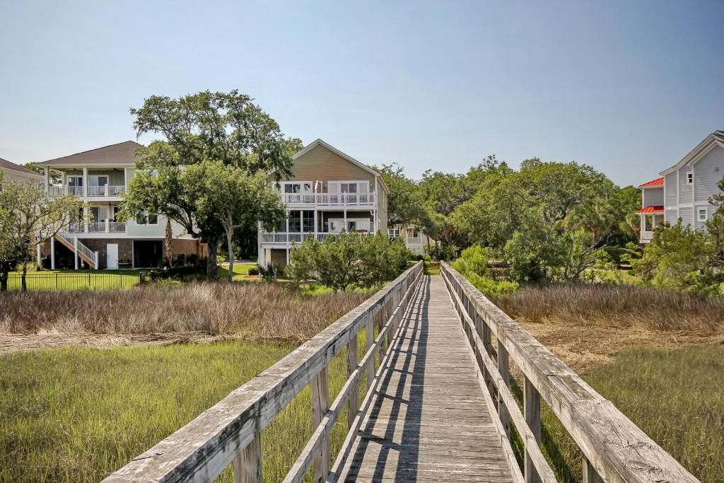 a wooden bridge over a marsh with houses in the background at Windy Lane Leisure in Pawleys Island