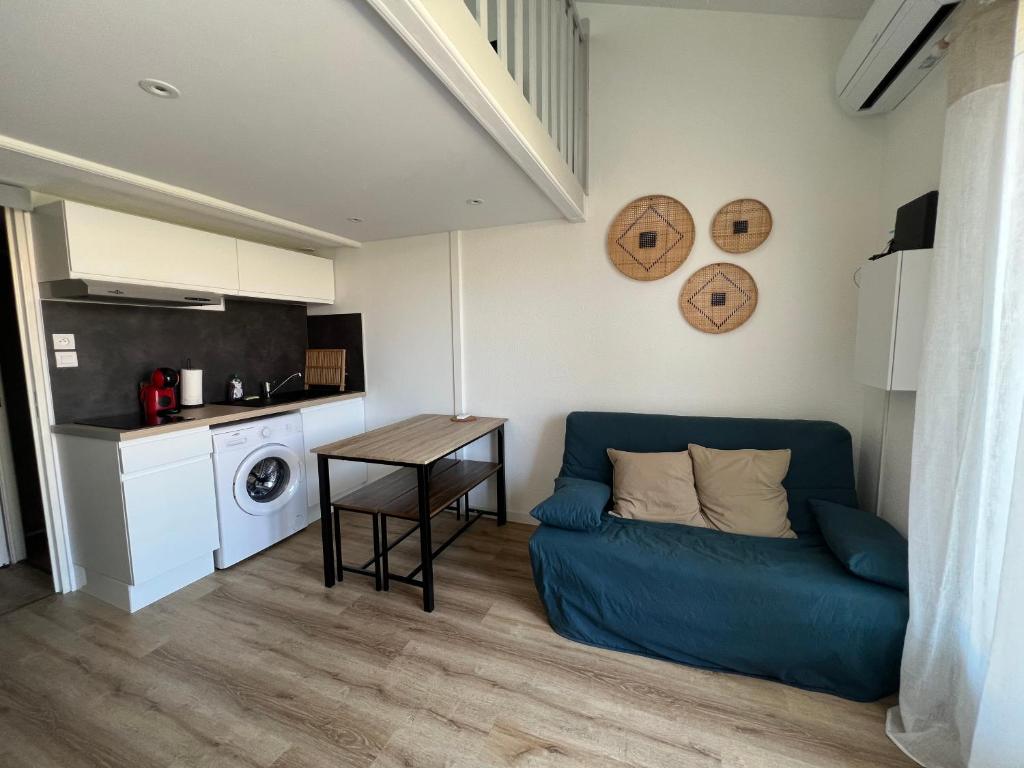 salon z niebieską kanapą i stołem w obiekcie Petite maison de vacances au bord de l'eau w mieście Leucate
