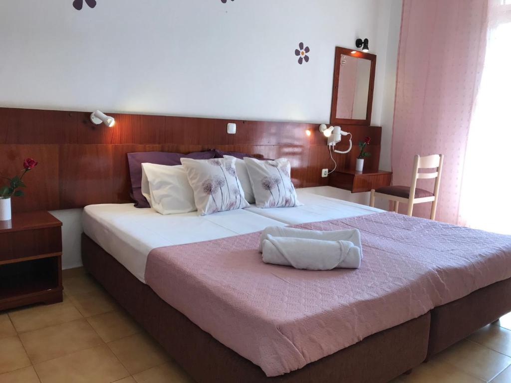 a bedroom with a large bed with a pink blanket at Dionysos Studios in Laganas