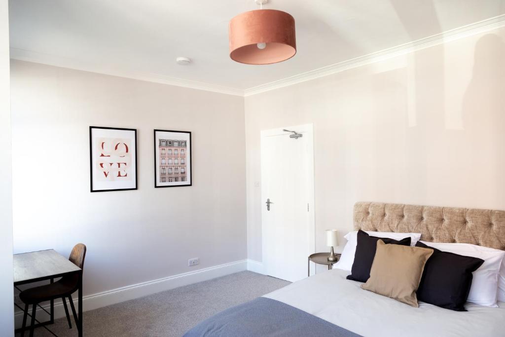 a white bedroom with a bed and a desk at Town Centre 4-bed House in Harrow