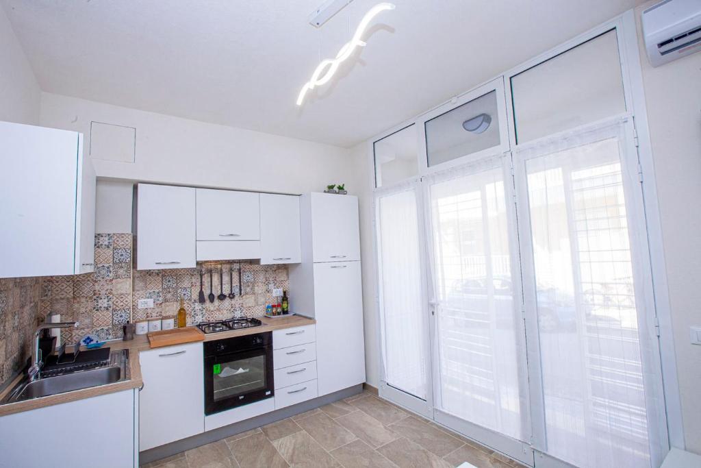uma cozinha com armários brancos e uma grande janela em Casa Elda em Marina di Ragusa