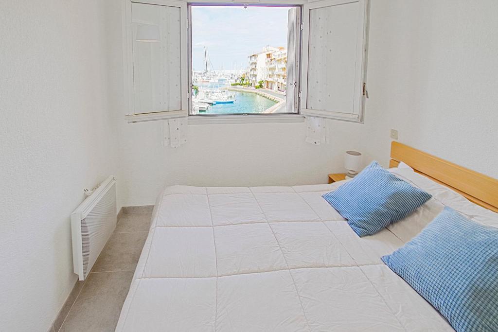 a white bedroom with a large bed and a window at T2 dans la marina du port de Canet - 2622 - in Canet-en-Roussillon