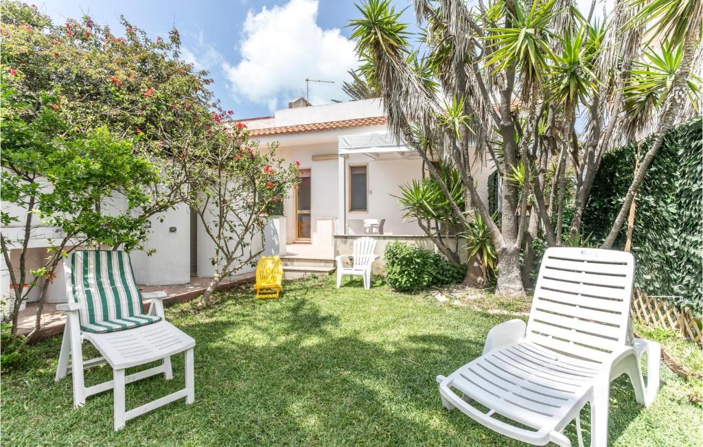 un patio con 2 sillas blancas y árboles en 3 Bedroom Nice Home In St, Maria Del Focallo, en Santa Maria del Focallo