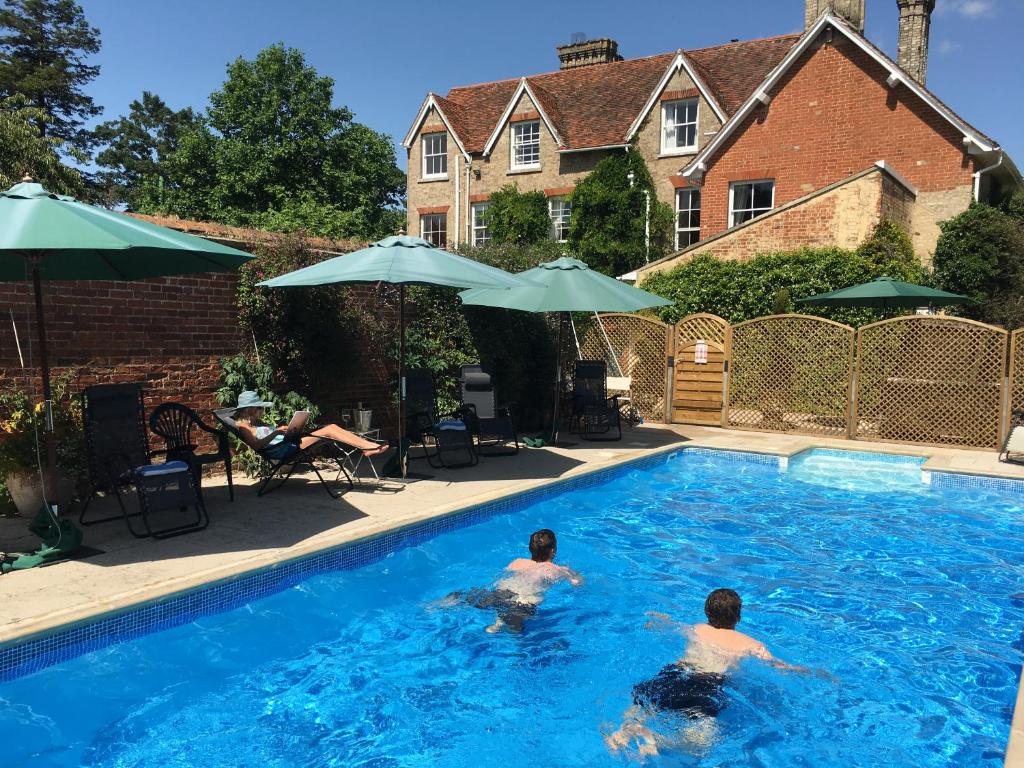 two men are swimming in a swimming pool at Rectory Manor in Lavenham