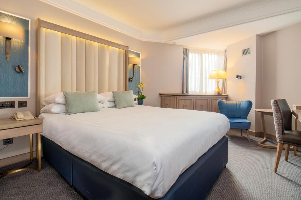 um quarto de hotel com uma cama grande e uma secretária em Danubius Hotel Regents Park em Londres