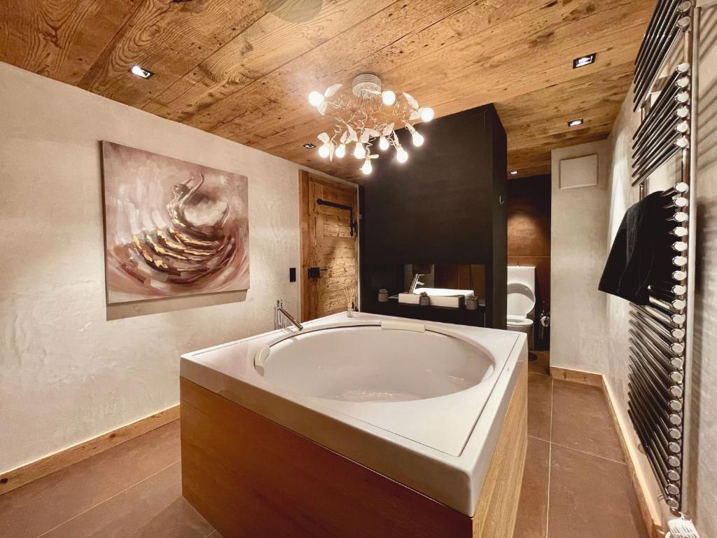 eine große Badewanne im Bad mit Kronleuchter in der Unterkunft Reseda 222 in Crans-Montana
