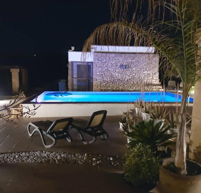 una piscina por la noche con una silla delante en RizzoRelax B&b io mammata e tu en Capilungo