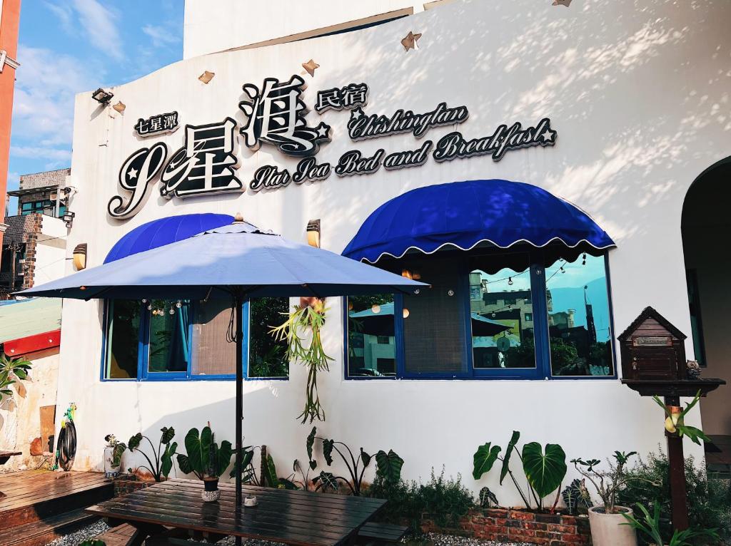 a building with a table and an umbrella outside at Qixingtan Xinghai B&amp;B in Dahan