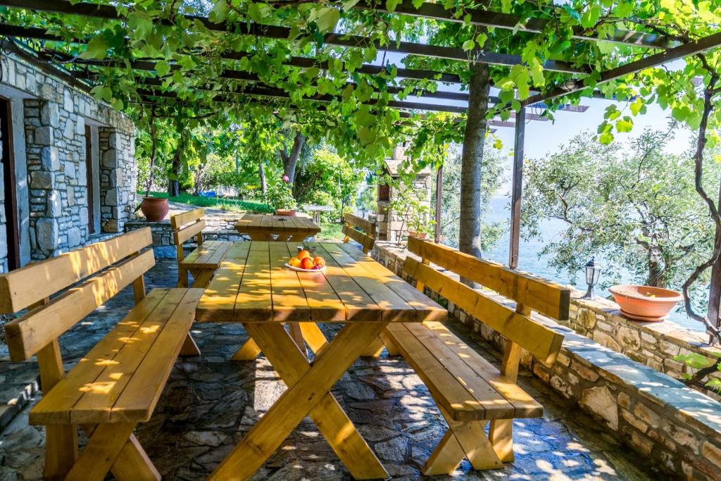 a wooden picnic table under a pergola at Petra Mare Apartments in Alyki