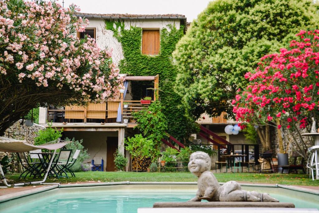 a statue in front of a swimming pool with flowers at Gites de la Soulondre in Lodève
