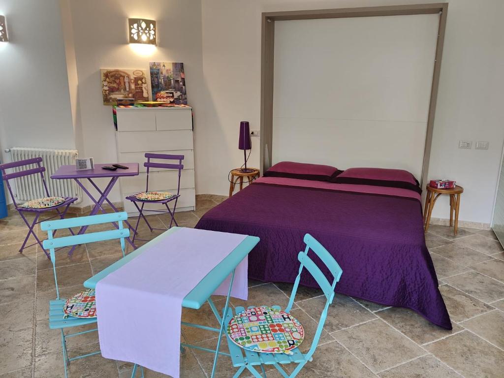 a bedroom with a purple bed with chairs and tables at Villa Alberto in Olbia