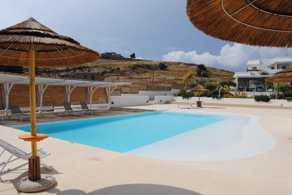una piscina con sombrilla y un complejo en Villa Aries - Rural Chic Experience, en Gela
